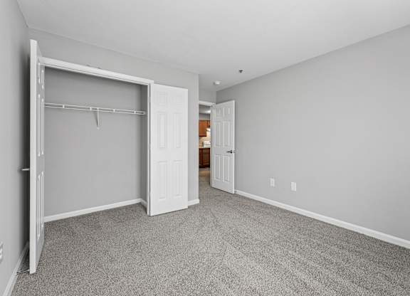 A room with a white door and a grey carpet.